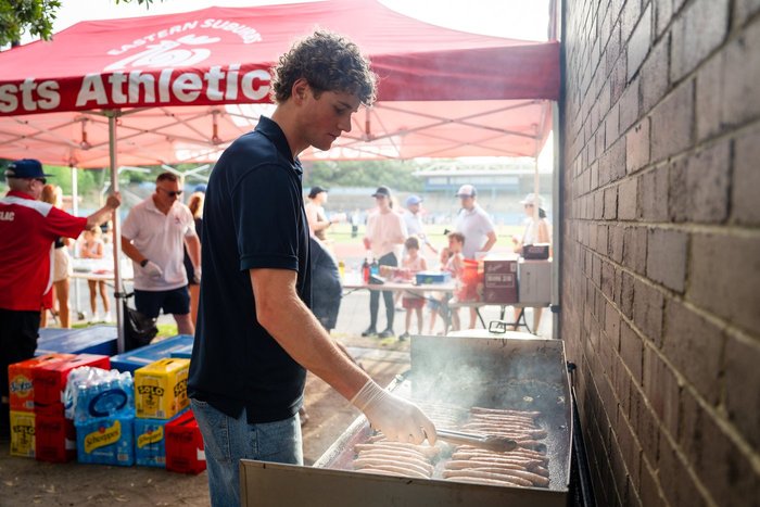 Volunteer cooking on the barbeque at Eastern Suburbs Little Athletics